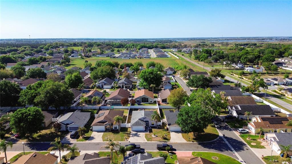 An aerial view shows a suburban neighborhood with single-family homes, green trees, and paved streets — 233 VERBENA STREET, DAVENPORT, FL
