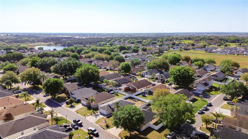 An aerial view shows a suburban neighborhood with single-family homes, green trees, and paved streets — 233 VERBENA STREET, DAVENPORT, FL