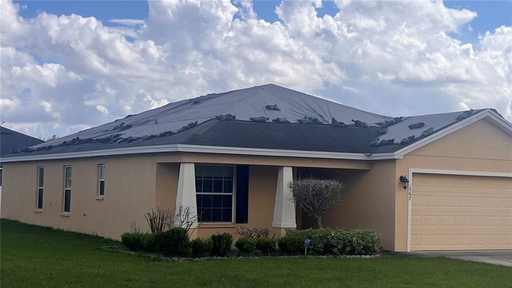 A tan single-story house with a two-car garage sits on a corner lot — 167 8TH STREET, LAKE HAMILTON, FL