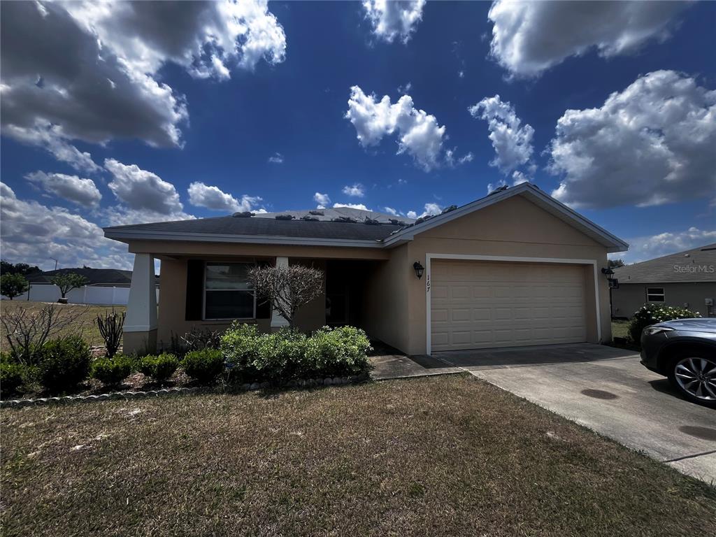 An open-concept kitchen with dark cabinets and a breakfast bar overlooks a carpeted living area — 167 8TH STREET, LAKE HAMILTON, FL