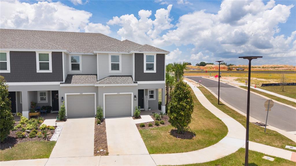 An exterior view of a two-story townhouse with a gray facade and two garages — 7771 WATERSCAPE, GROVELAND, FL
