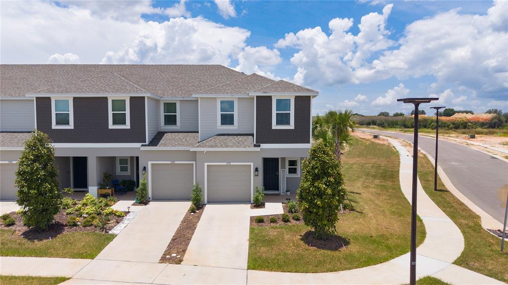 An exterior view of a two-story townhouse with a gray facade and attached garages — 7771 WATERSCAPE, GROVELAND, FL