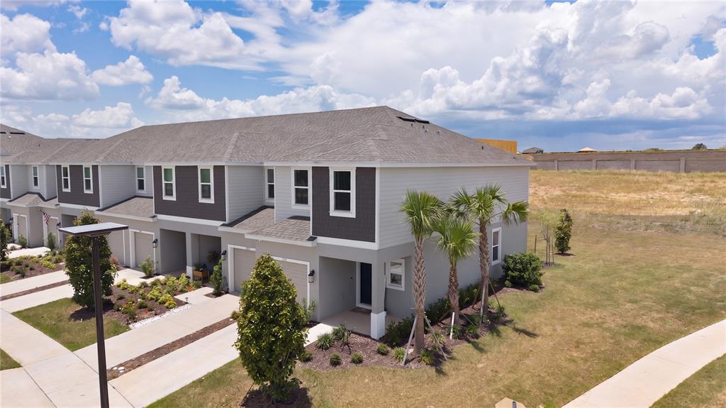 An aerial view shows a two-story townhouse with a gray exterior and a shingled roof — 7771 WATERSCAPE, GROVELAND, FL