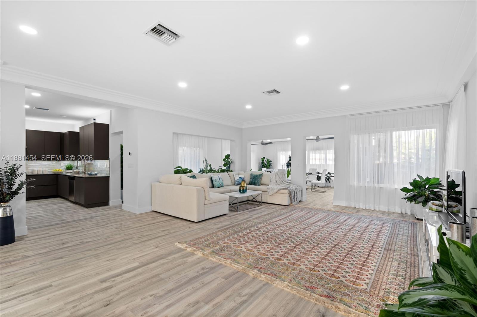 A spacious open-concept living room features a large sectional sofa, patterned rug, and dark cabinetry — 1155 Tyler St, Hollywood FL 33019, HOLLYWOOD, FL
