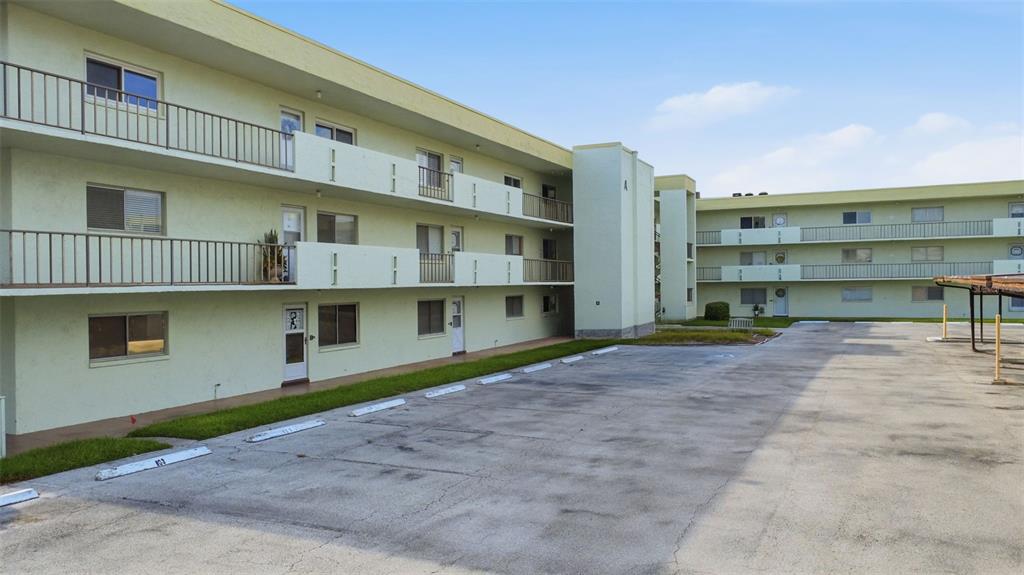 An exterior view of a multi-story apartment building with a parking lot in front — 1130 N LAKE PARKER AVENUE UNIT A205, LAKELAND, FL