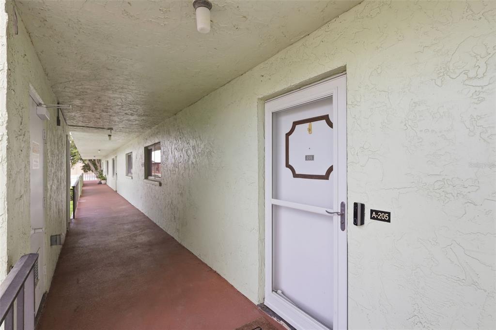 An exterior walkway leads to the entrance of unit A-205 in a multi-story building — 1130 N LAKE PARKER AVENUE UNIT A205, LAKELAND, FL