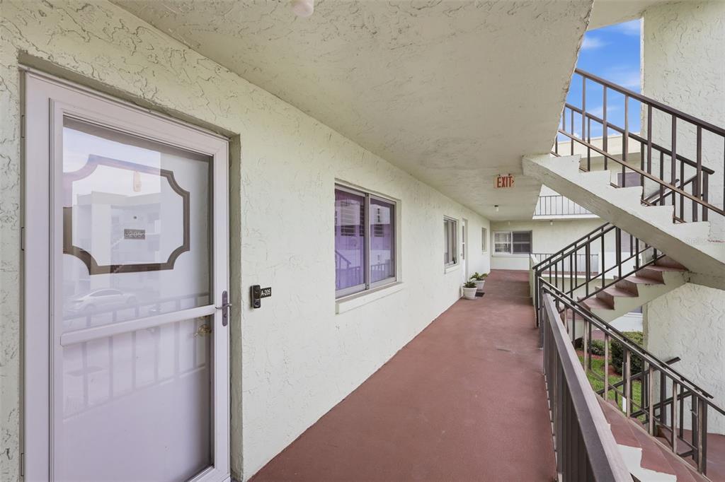 An exterior walkway with a staircase, a screen door, and a window on a building — 1130 N LAKE PARKER AVENUE UNIT A205, LAKELAND, FL