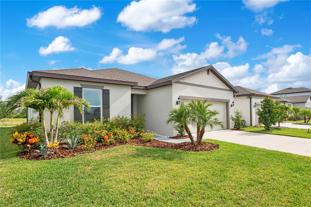 A single-story house with a beige stucco exterior, a two-car garage, and landscaped front yard — 11237 ROLLING FORK TRAIL, PARRISH, FL