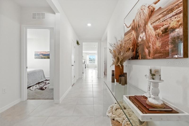 A bright hallway with white tile flooring leads to an open living area — 33504 COPPER HILL WAY, SORRENTO, FL