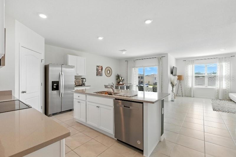 A modern kitchen with white cabinets and stainless steel appliances opens to a living area — 33504 COPPER HILL WAY, SORRENTO, FL