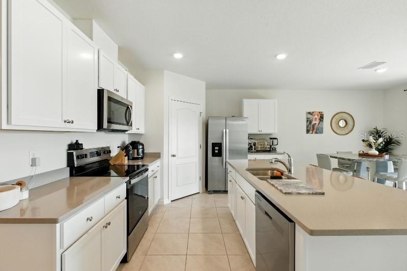 A modern kitchen features white cabinets, quartz countertops, stainless steel appliances, and an island — 33504 COPPER HILL WAY, SORRENTO, FL