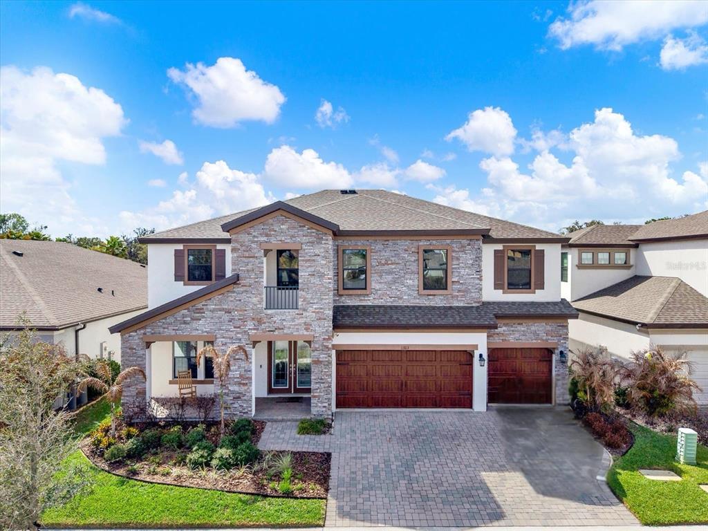 A two-story suburban house features a stone facade, a paved driveway, and a three-car garage — 13113 WILDFLOWER MEADOW DRIVE, RIVERVIEW, FL