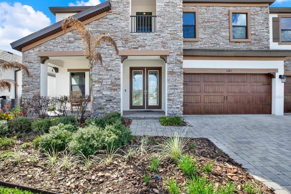 A two-story house exterior features stone veneer, a double front door, and a paved driveway — 13113 WILDFLOWER MEADOW DRIVE, RIVERVIEW, FL