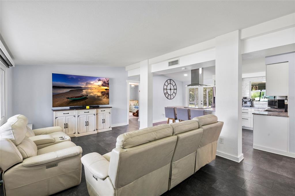 A living room with white leather sofas, a large television, and an open kitchen area — 2287 MANOR BOULEVARD N, CLEARWATER, FL