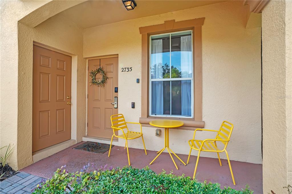 A front porch features two yellow chairs, a small table, and two tan entry doors — 2735 CALABRIA AVENUE, DAVENPORT, FL
