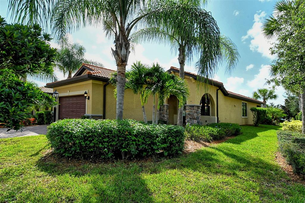 A single-story house with a tan stucco exterior, a tile roof, and palm trees in front — 6743 HAVERHILL COURT, BRADENTON, FL