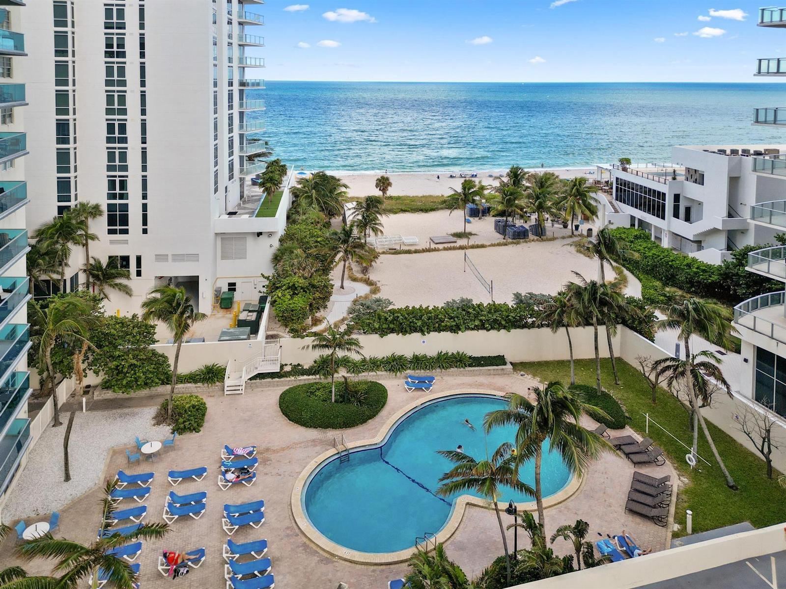 An elevated view of a swimming pool, palm trees, a sandy beach, and the ocean — 4001 S Ocean Drive # 8E, Hollywood FL 33019, HOLLYWOOD, FL