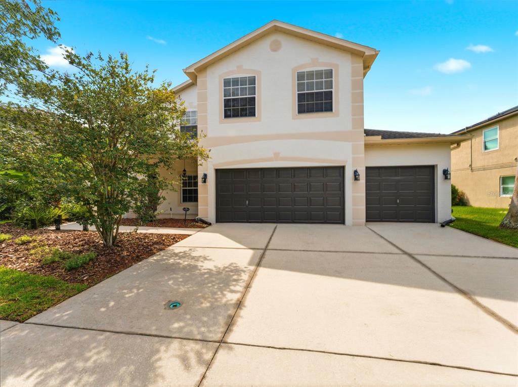 A two-story suburban house features a three-car garage and a concrete driveway — 14843 HERONGLEN DRIVE, LITHIA, FL