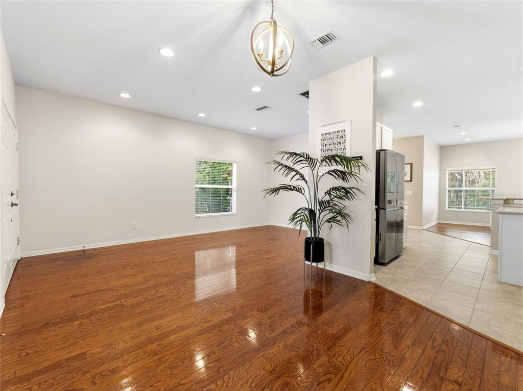 A room with hardwood floors, a central plant, and a transition to a tiled kitchen — 14843 HERONGLEN DRIVE, LITHIA, FL