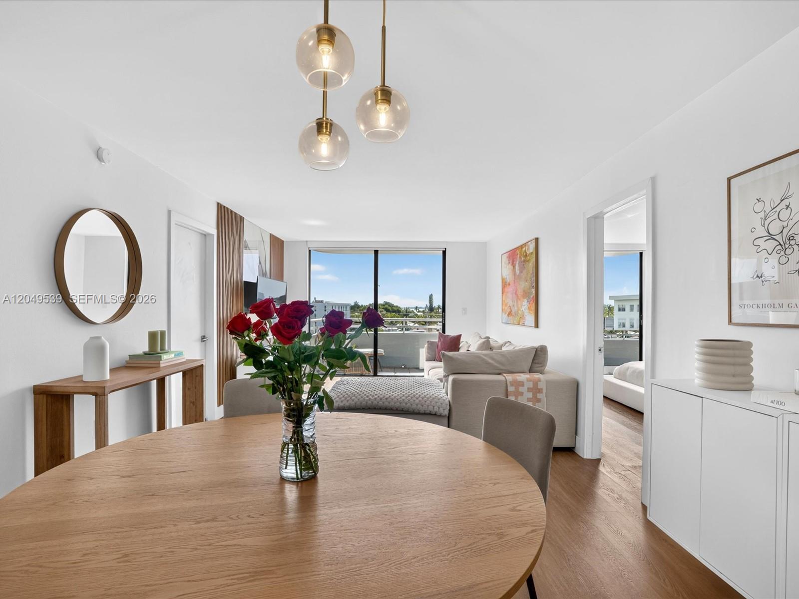 A dining area with a round wooden table and pendant lighting overlooks a living room — 8201 Byron Ave # 502, Miami Beach FL 33141, MIAMI BEACH, FL