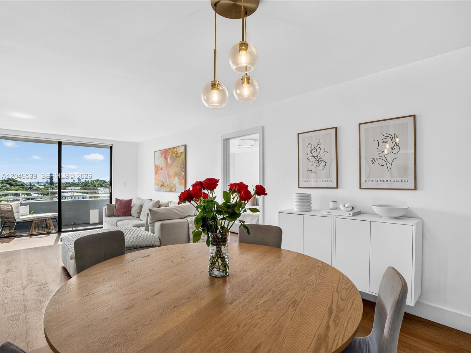 A dining room features a round wooden table, grey chairs, and a modern pendant light — 8201 Byron Ave # 502, Miami Beach FL 33141, MIAMI BEACH, FL