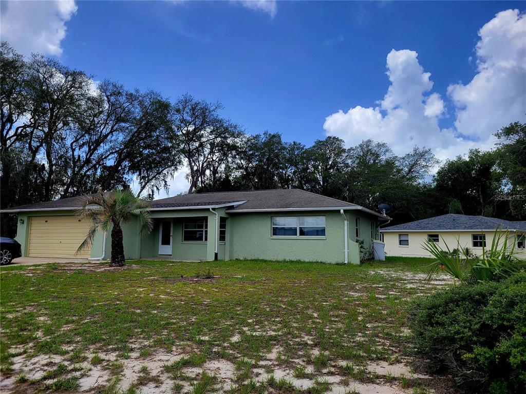 A light green single-story house with a tan garage door and a palm tree — 9022 LINGROVE ROAD, WEEKI WACHEE, FL