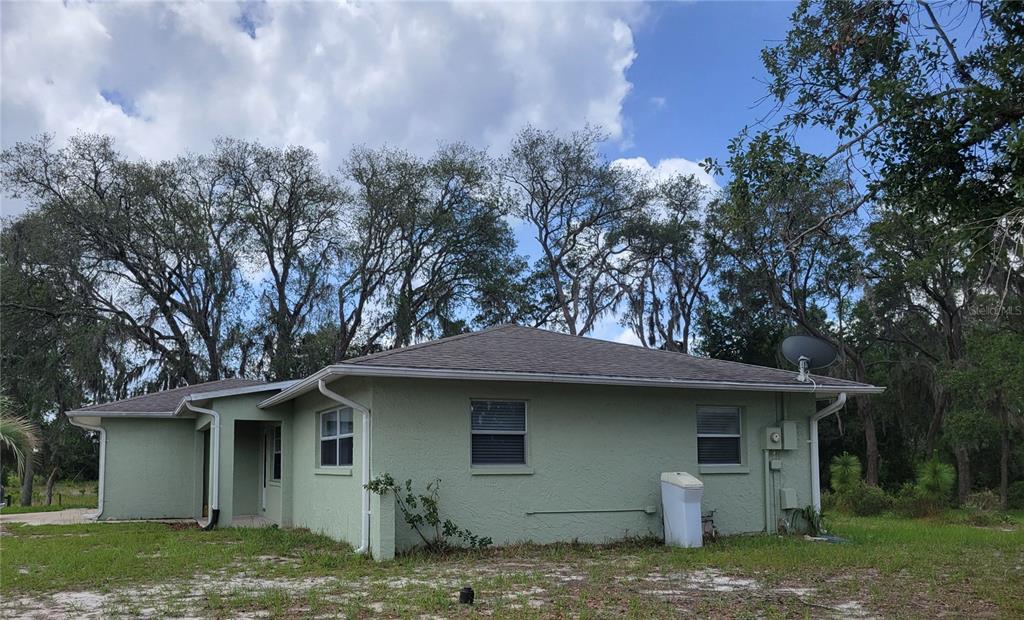 The exterior of a light green, single-story house with a hip roof and mature trees — 9022 LINGROVE ROAD, WEEKI WACHEE, FL