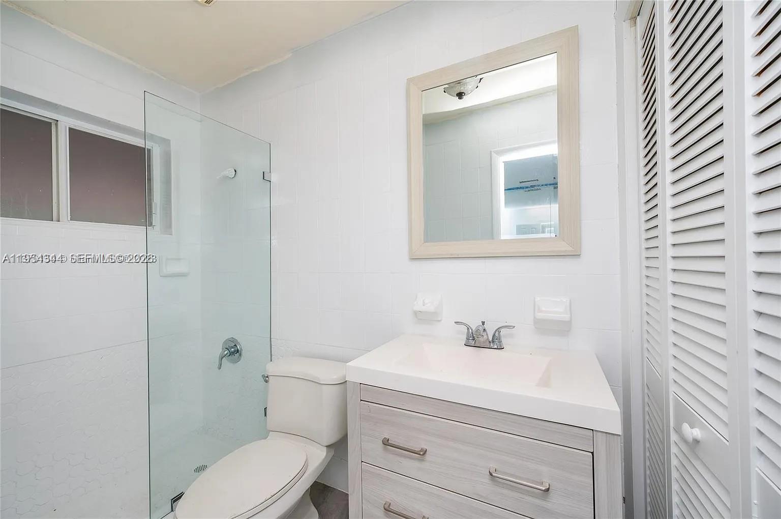 A bathroom features a glass-enclosed shower, a white toilet, and a light wood vanity — 11950 SW 182nd Ter, Miami FL 33177, MIAMI, FL