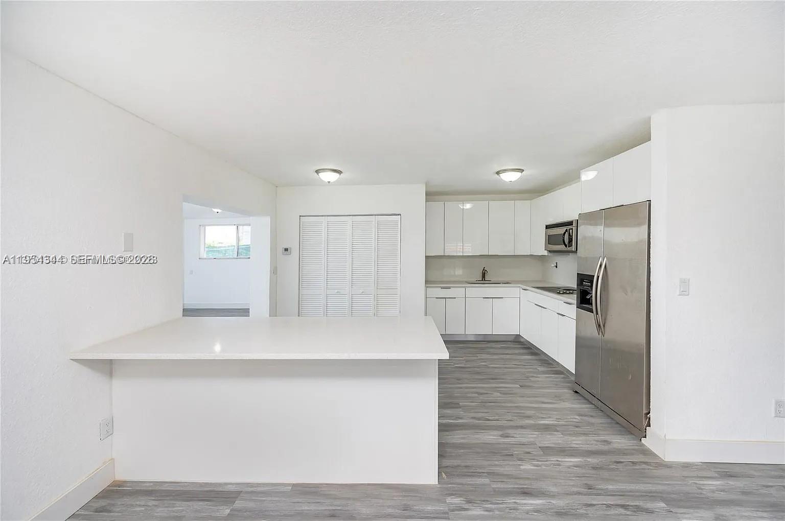 A modern kitchen features white cabinets, stainless steel appliances, and a white peninsula countertop — 11950 SW 182nd Ter, Miami FL 33177, MIAMI, FL