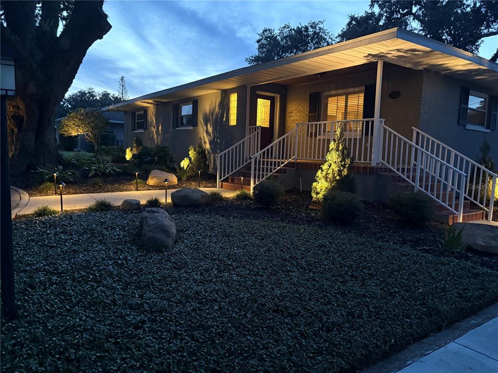 A single-story house with a white railing porch, exterior lighting, and a landscaped front yard — 1522 DEL CREST PLACE, LAKELAND, FL