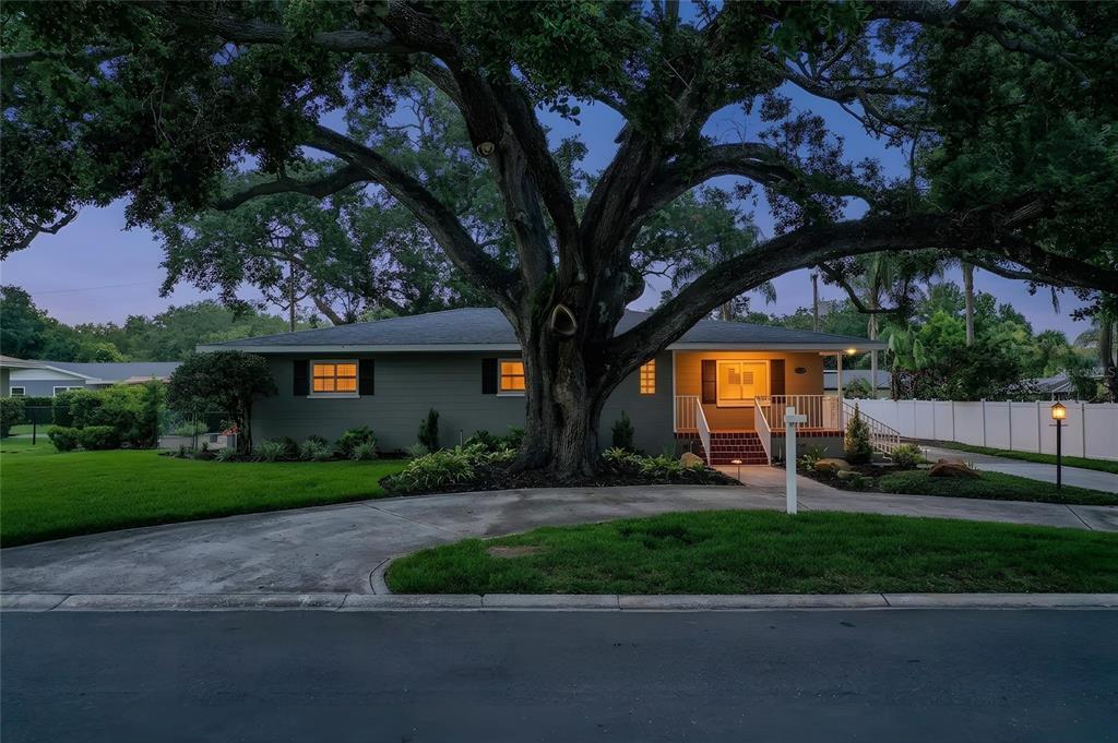 A single-story house with a large oak tree in the front yard at dusk — 1522 DEL CREST PLACE, LAKELAND, FL
