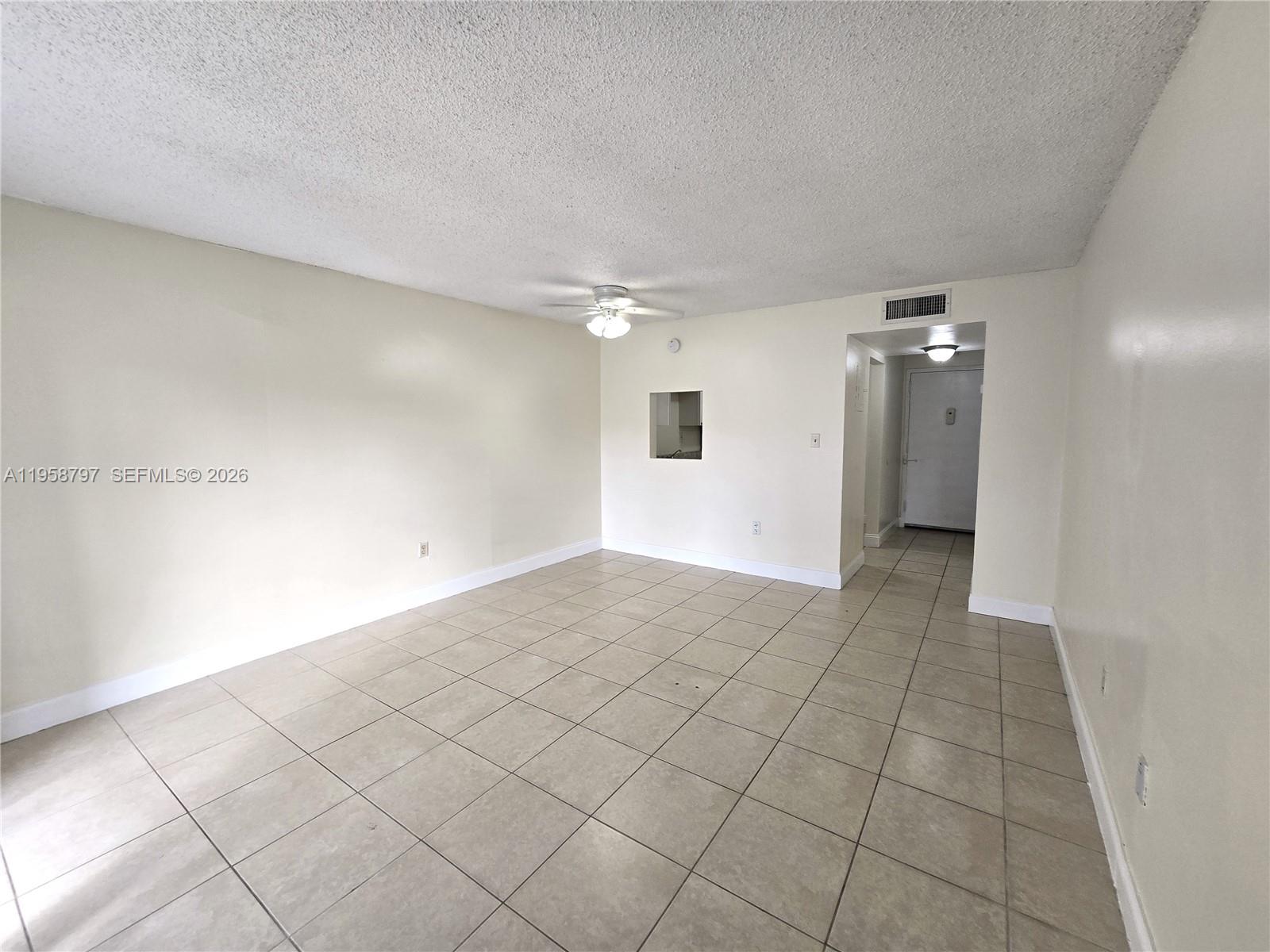An empty living room features beige tile flooring, white walls, and a ceiling fan — 4334 NW 9th Ave # 1B, Deerfield Beach FL 33064, DEERFIELD BEACH, FL
