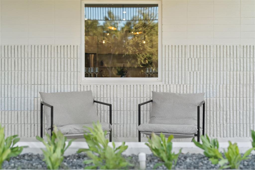 Two gray chairs sit on a patio in front of a white textured brick wall — 438 SKYFIELD COURT, LADY LAKE, FL