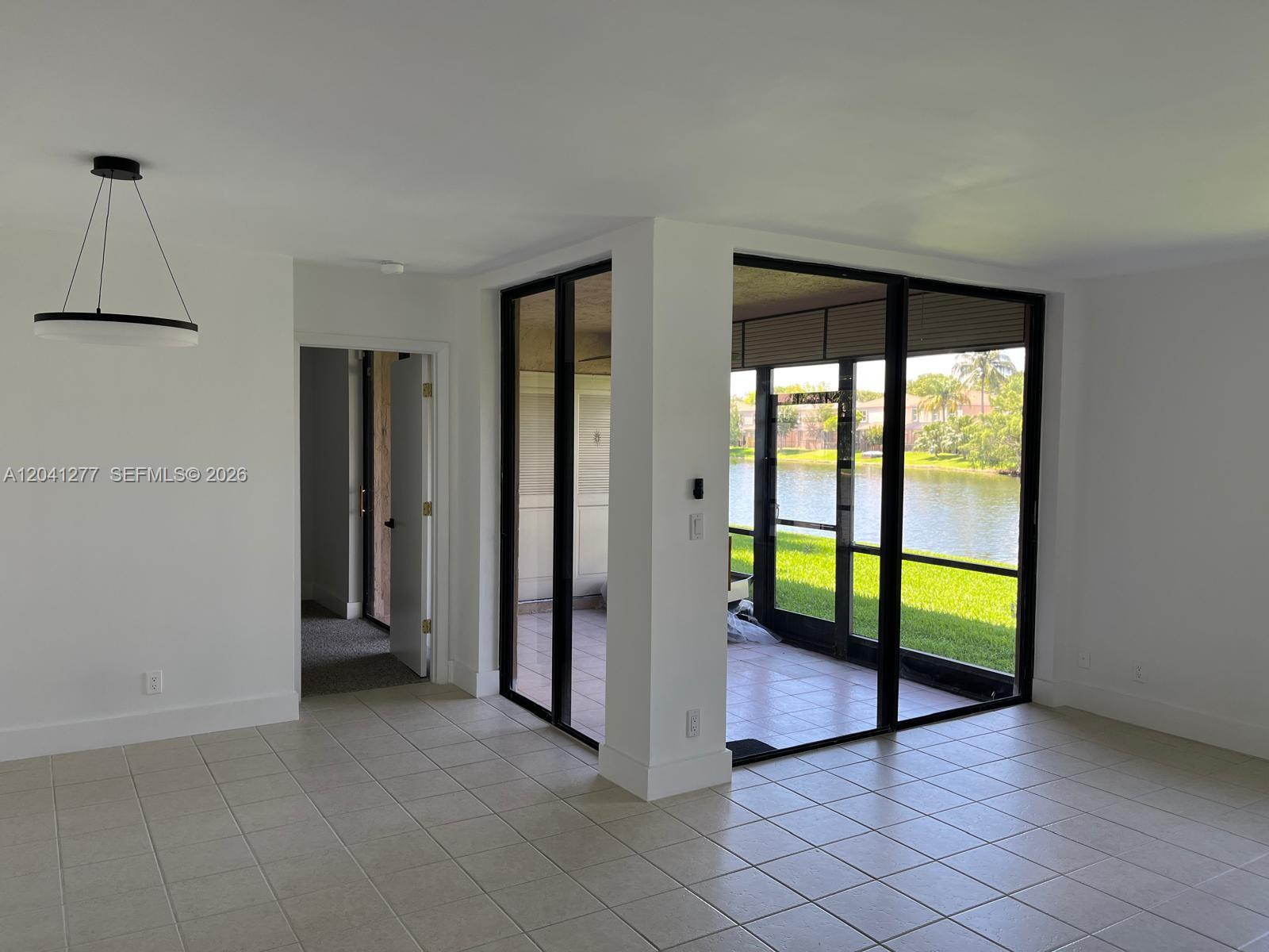 A bright room with tiled floors features a modern pendant light and a screened patio — PLANTATION, FL