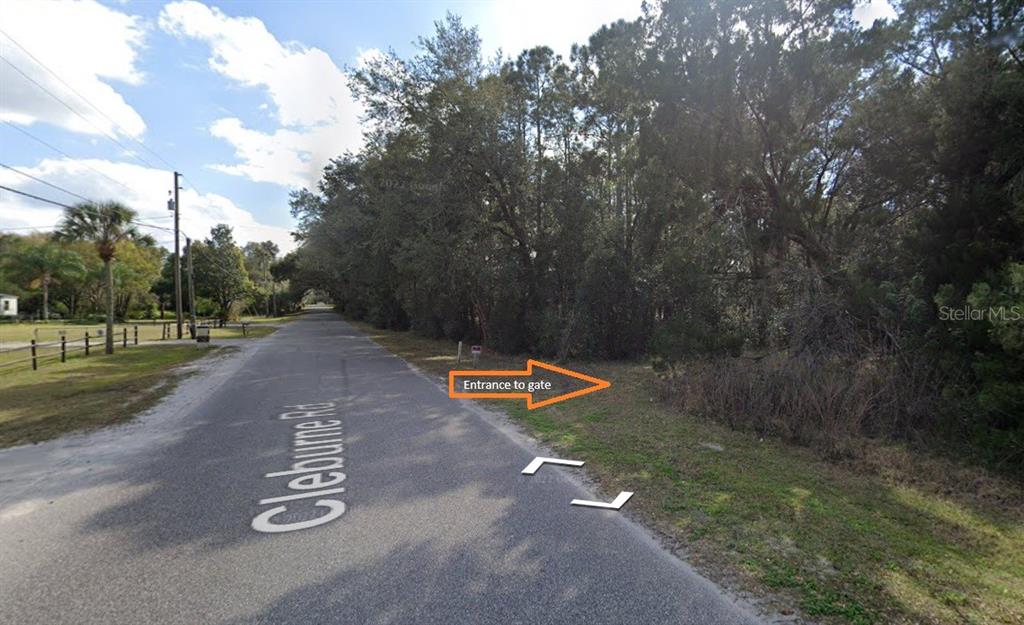A view of a paved road with an arrow pointing toward a wooded lot entrance — 2850 CLEBURNE ROAD, ORLANDO, FL