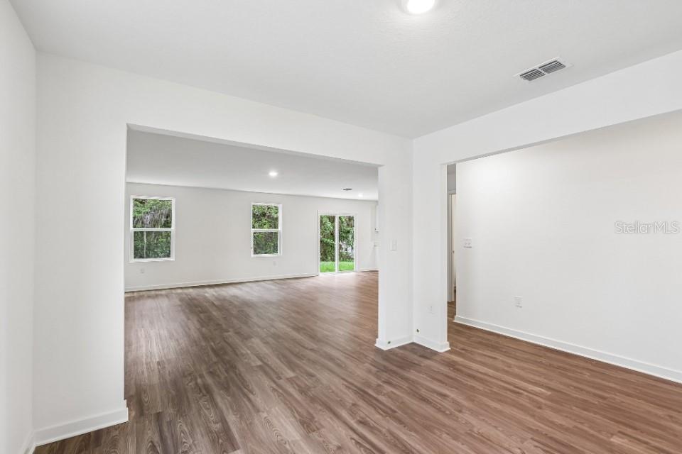 An interior view shows a living area with wood-look flooring and white walls — 16253 NW 143RD WAY, ALACHUA, FL