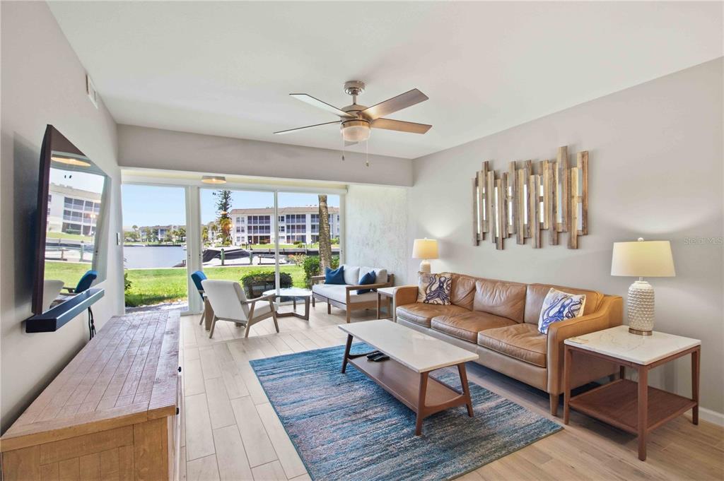 A living room features a leather sofa, a blue area rug, and a waterfront view — 4340 FALMOUTH DRIVE UNIT 104, LONGBOAT KEY, FL