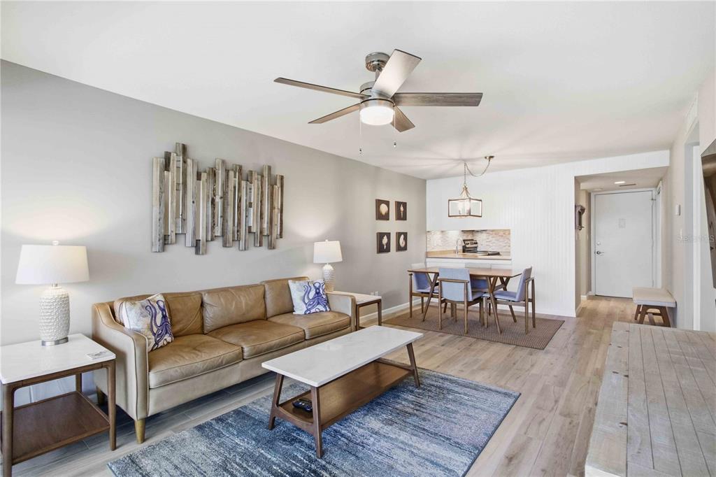 A living room with a leather sofa, coffee table, dining area, and light wood flooring — 4340 FALMOUTH DRIVE UNIT 104, LONGBOAT KEY, FL