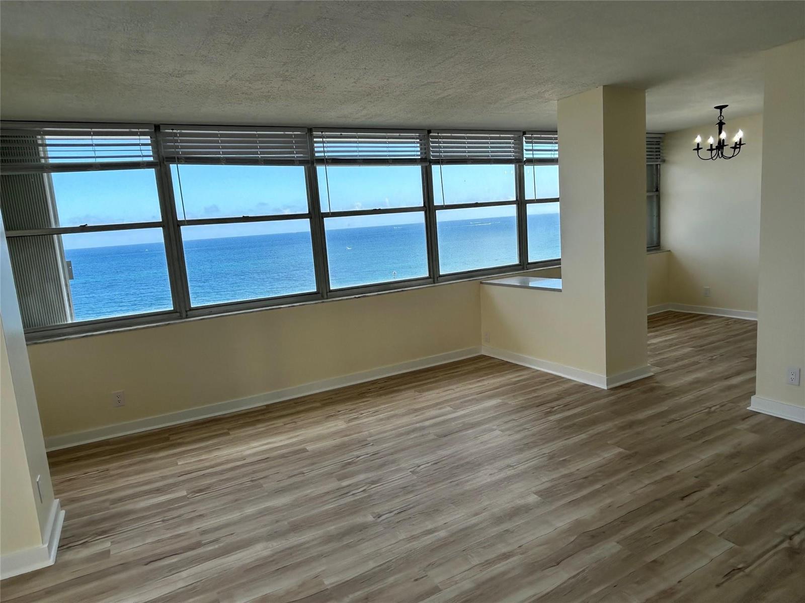 An empty room with light wood-look flooring and large windows offering an ocean view — 111 Briny Avenue # 1401, Pompano Beach FL 33062, POMPANO BEACH, FL