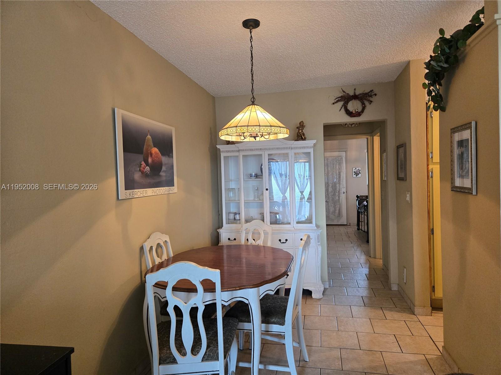 A dining area features a wooden table, white chairs, a hutch, and a pendant light — 900 SW 11th Ave # 12A, Hallandale Beach FL 33009, HALLANDALE BEACH, FL
