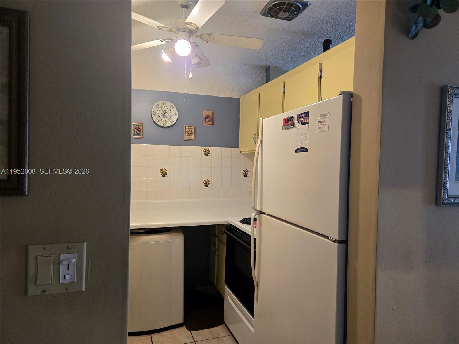 A kitchen features yellow cabinets, a white refrigerator, a stove, and a laundry appliance — 900 SW 11th Ave # 12A, Hallandale Beach FL 33009, HALLANDALE BEACH, FL