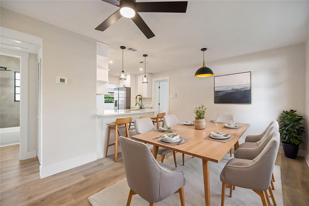 A dining room with a wooden table and chairs sits adjacent to a kitchen island — 11014 58TH STREET N, PINELLAS PARK, FL