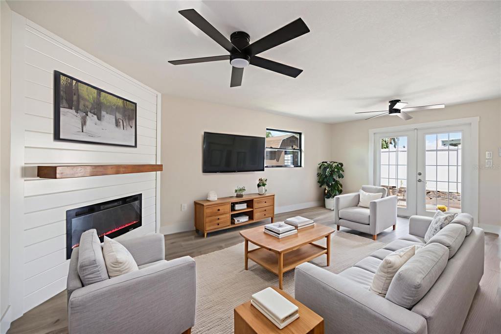A living room features a fireplace with a shiplap wall, light wood furniture, and gray seating — 11014 58TH STREET N, PINELLAS PARK, FL