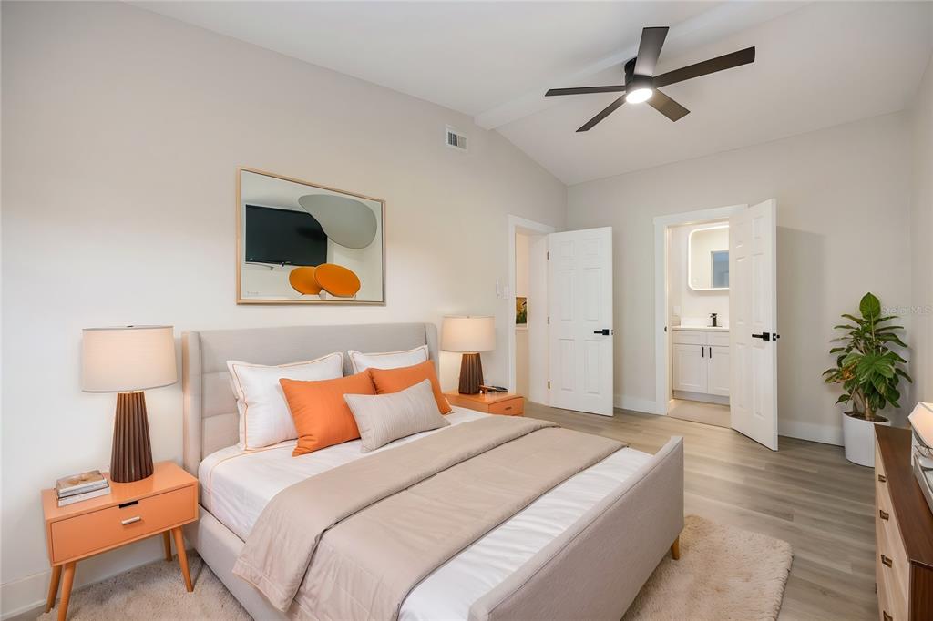 A bedroom features a bed with orange pillows, two nightstands, and an attached bathroom — 11014 58TH STREET N, PINELLAS PARK, FL