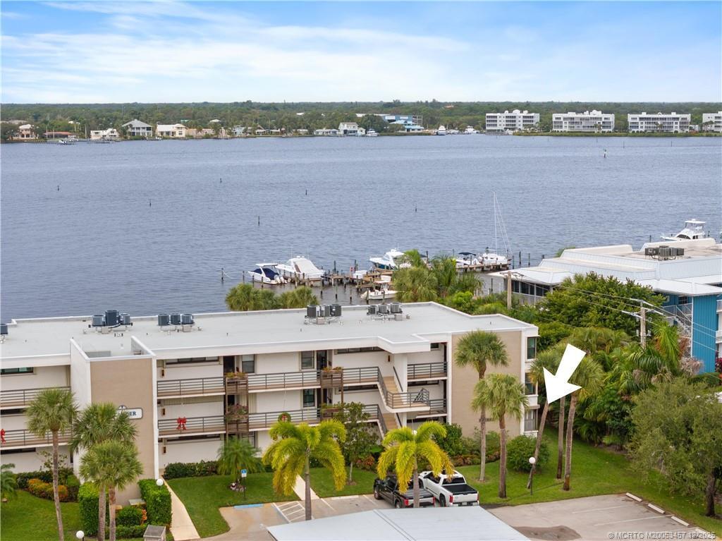 An exterior view of a multi-story apartment building with a waterfront dock and palm trees — 1950 SW Palm City Road # 107, Stuart FL 34994, STUART, FL