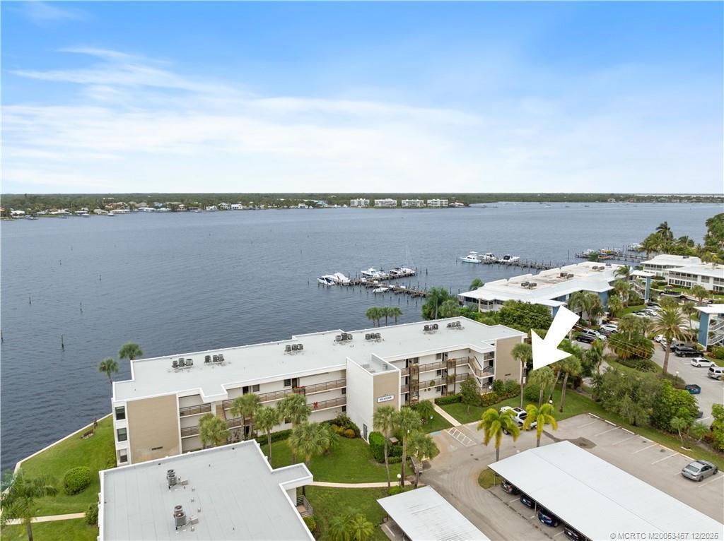 An aerial view shows a multi-story apartment building situated along a waterfront with boat docks — 1950 SW Palm City Road # 107, Stuart FL 34994, STUART, FL