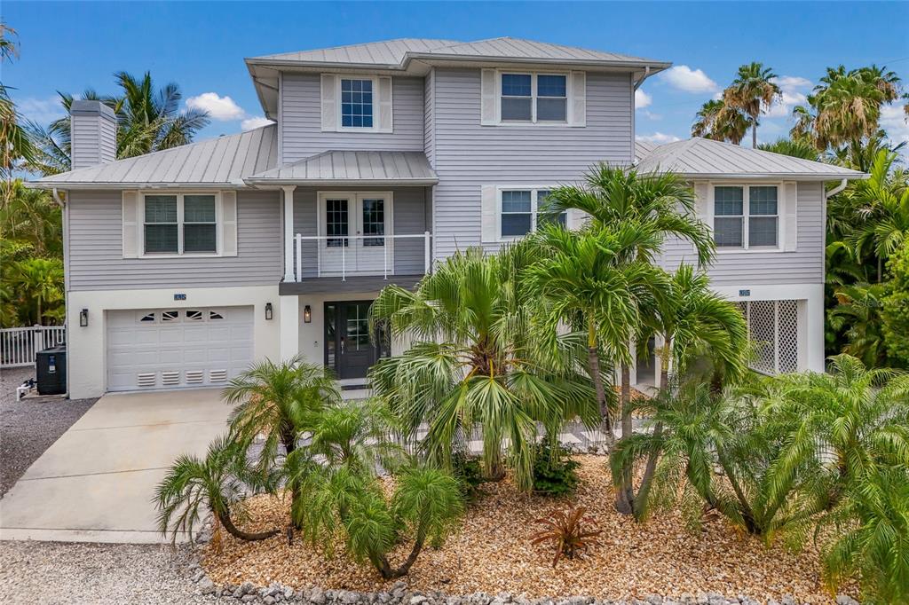 A two-story light gray house with a metal roof and palm trees in the front — 115 HAMMOCK ROAD, ANNA MARIA, FL