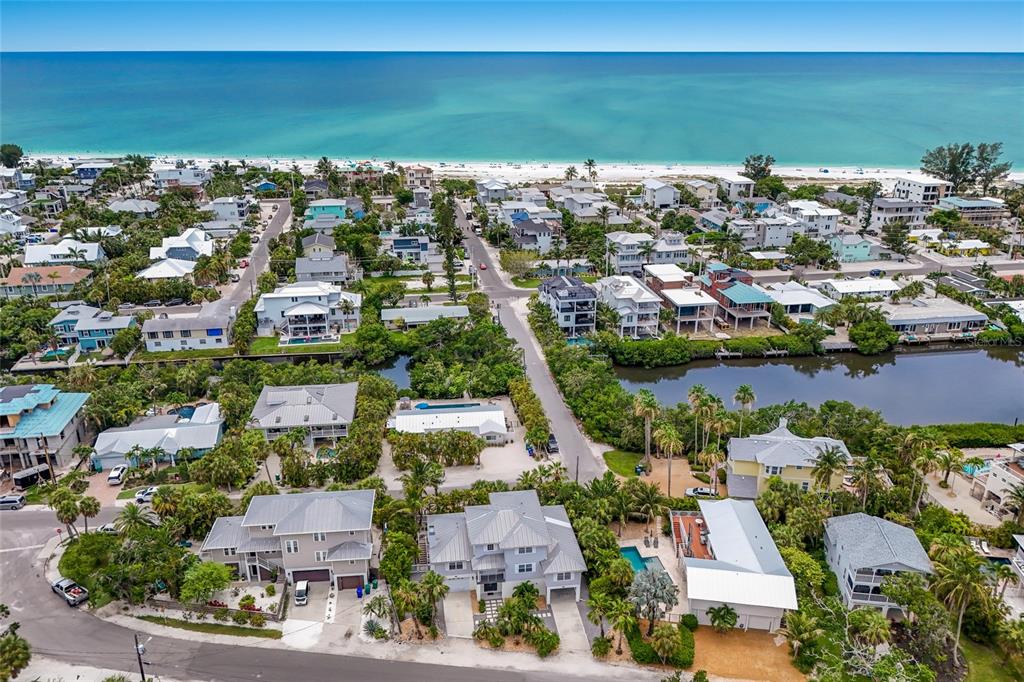 An aerial view shows coastal homes near a beach, a canal, and lush vegetation — 115 HAMMOCK ROAD, ANNA MARIA, FL