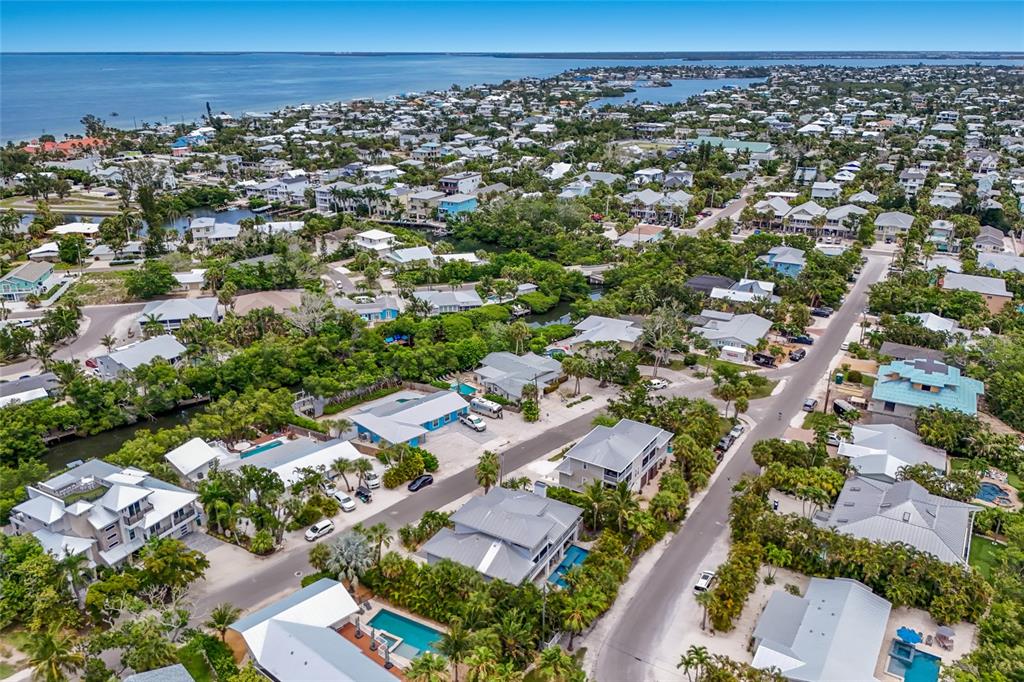 An aerial view shows a coastal neighborhood with houses, swimming pools, and lush vegetation — 115 HAMMOCK ROAD, ANNA MARIA, FL