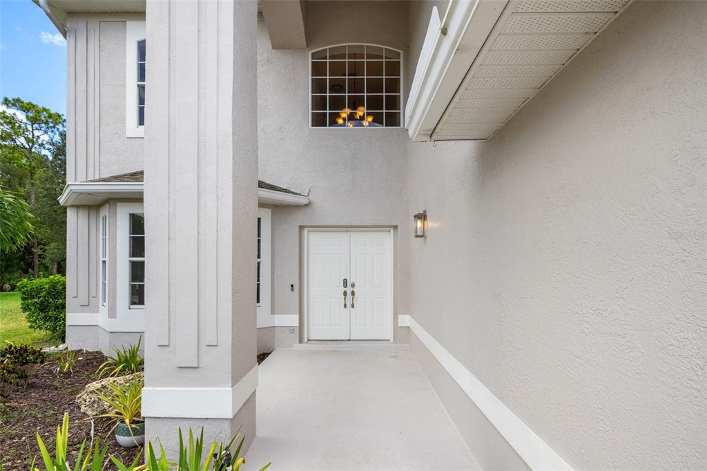 A view of a home entrance with double white doors, a large pillar, and windows — 4705 78TH COURT E, BRADENTON, FL
